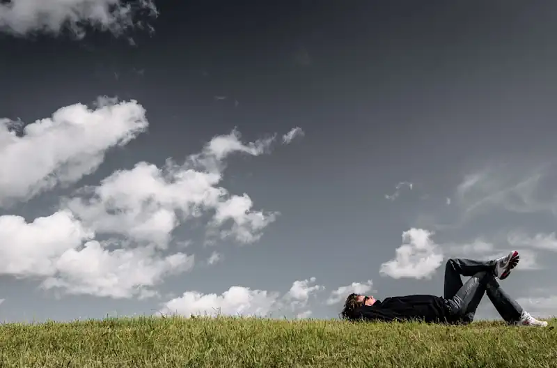 Auszeit nach einer langen Fahrt - ein Mann liegt im Gras und schaut in den Himmel